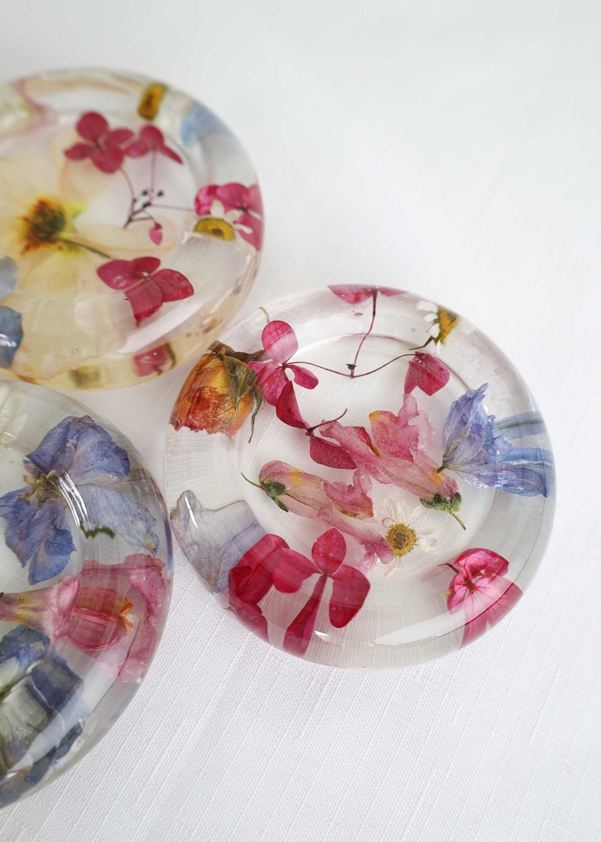 Resin Trinket Dish, clear round resin with embedded pink, blue and yellow dried flowers and delicate botanical details.