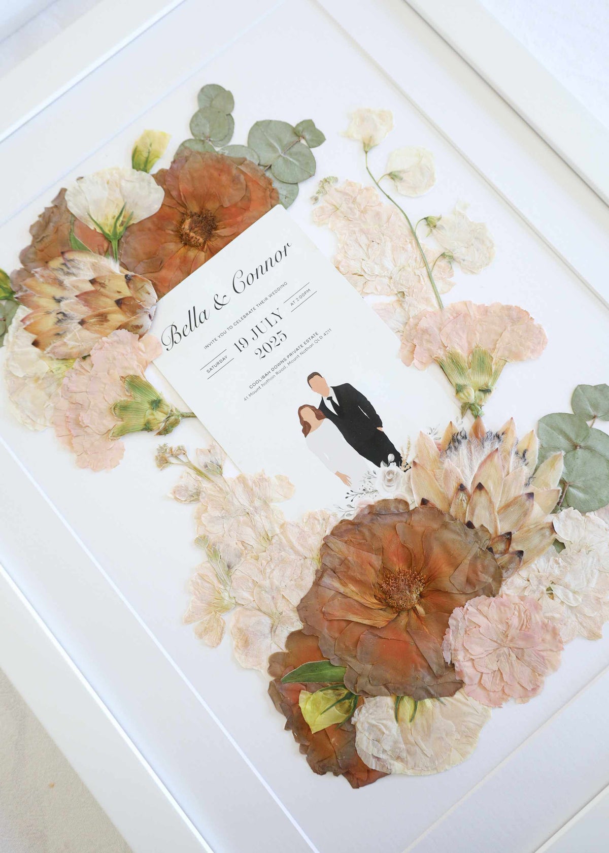 Framed pressed bridal flowers with wedding vows, invitation, and photo display