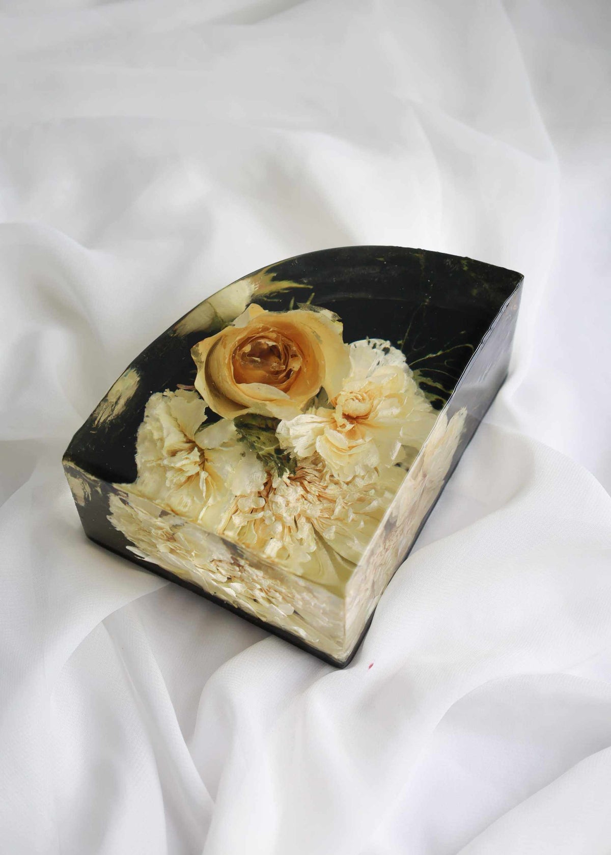 Resin bookend from a Set of Resin Display with preserved cream flowers and an orange rose in a black-backed block